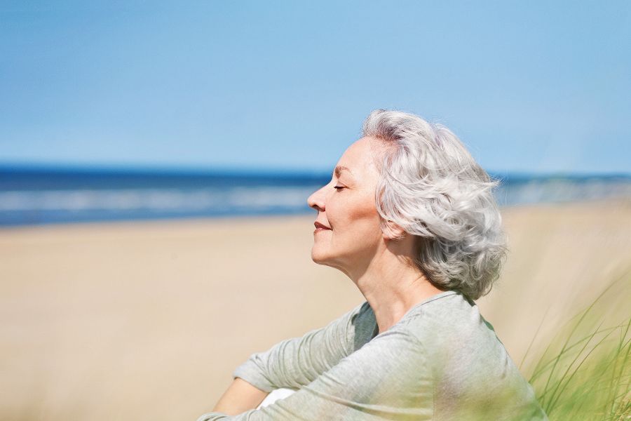 attraktive, grauhaarige Frau genieÃ?t das Meer